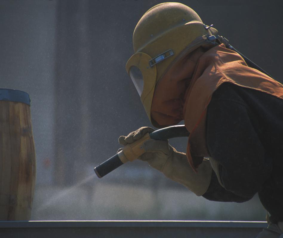 A person sandblasting using silica sand.